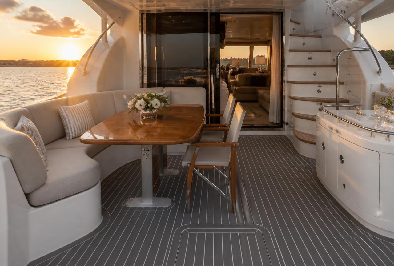 Yacht aft cockpit with dark grey synthetic teak decking and white caulk lines at sunset