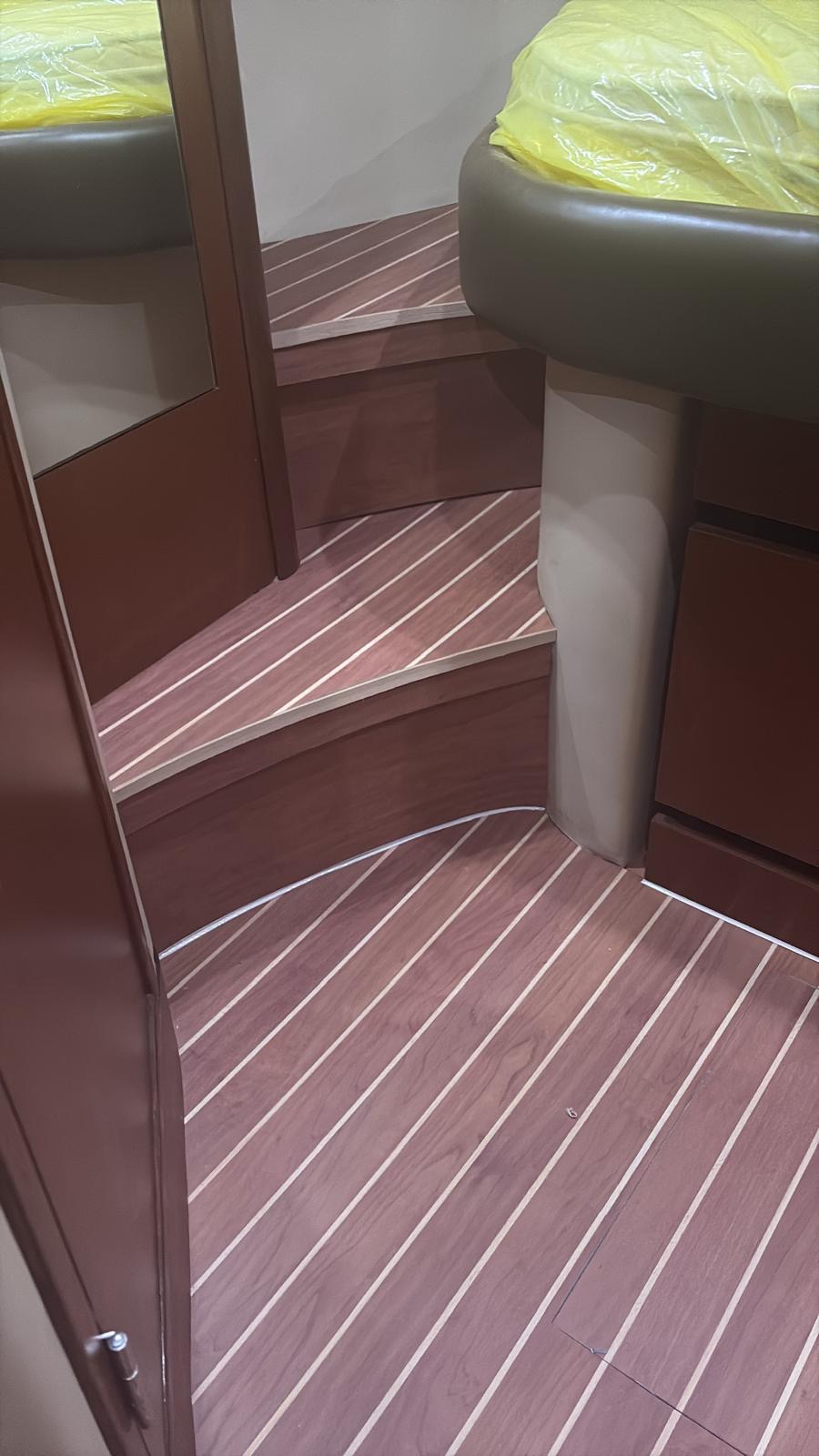 Wide view of a yacht cabin with curved synthetic teak steps matching the sole and cabinetry