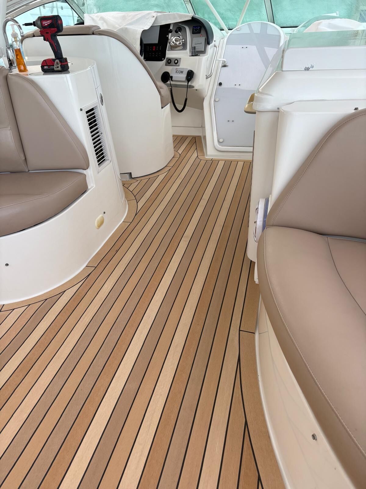 Express cruiser cockpit sole in honey synthetic teak with black caulk lines running past the helm seat and companionway door