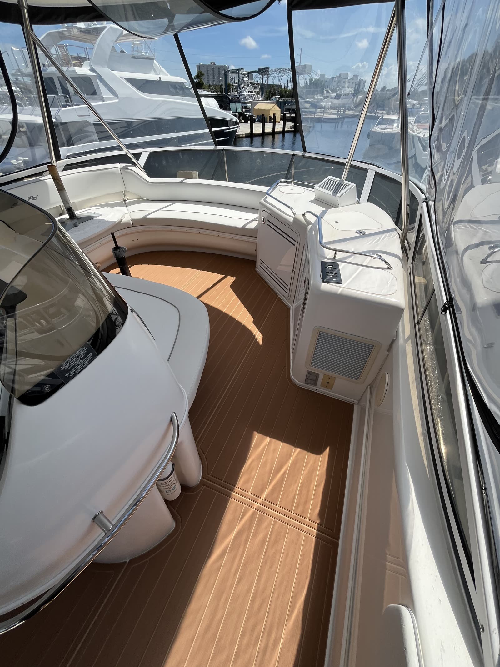 Enclosed bridge deck lounge with new synthetic teak decking and a Florida marina beyond the clears