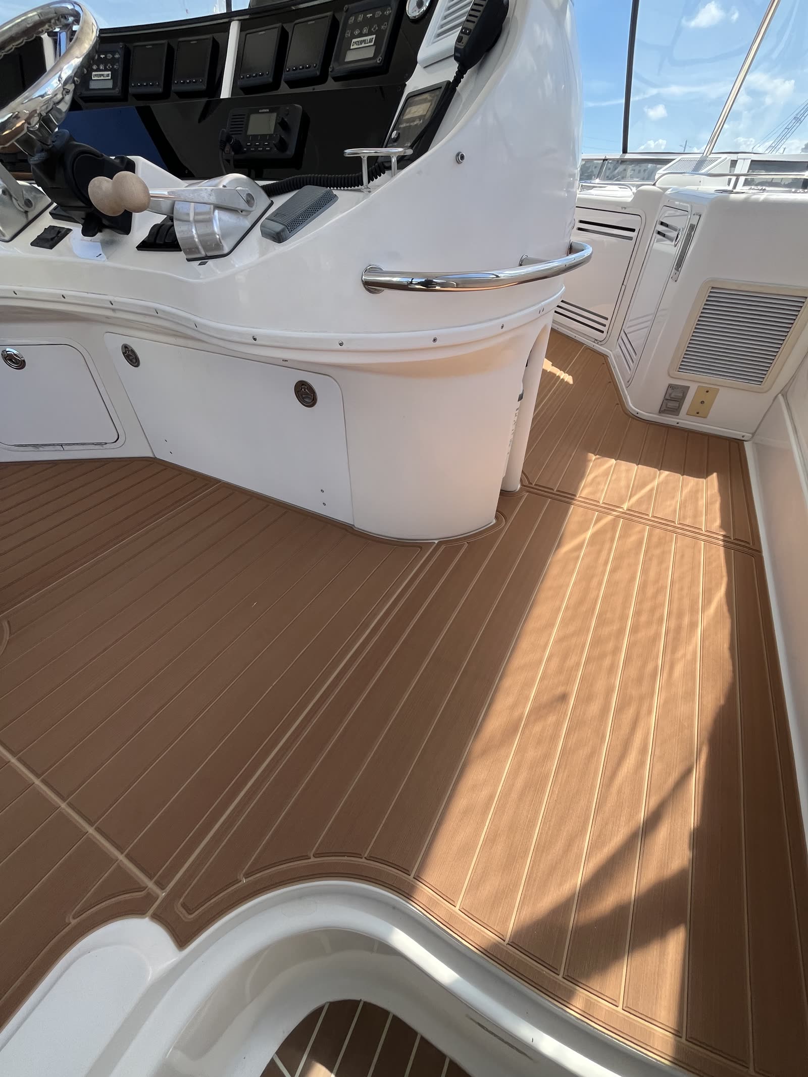 Synthetic teak deck at the helm station of a motor yacht with the companionway hatch in the foreground