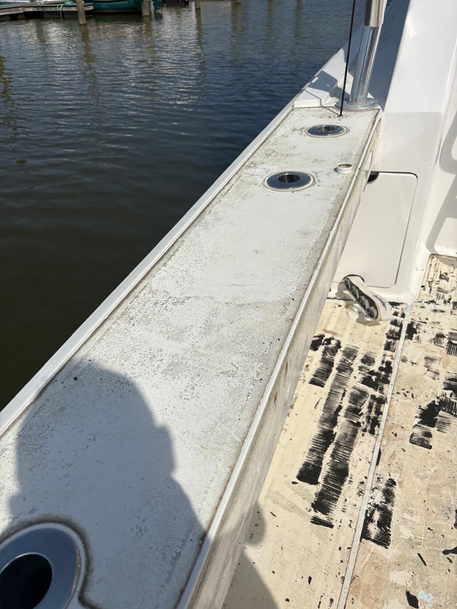 Chalky bare fibreglass gunwale cap with stainless rod holders before new synthetic teak is fitted