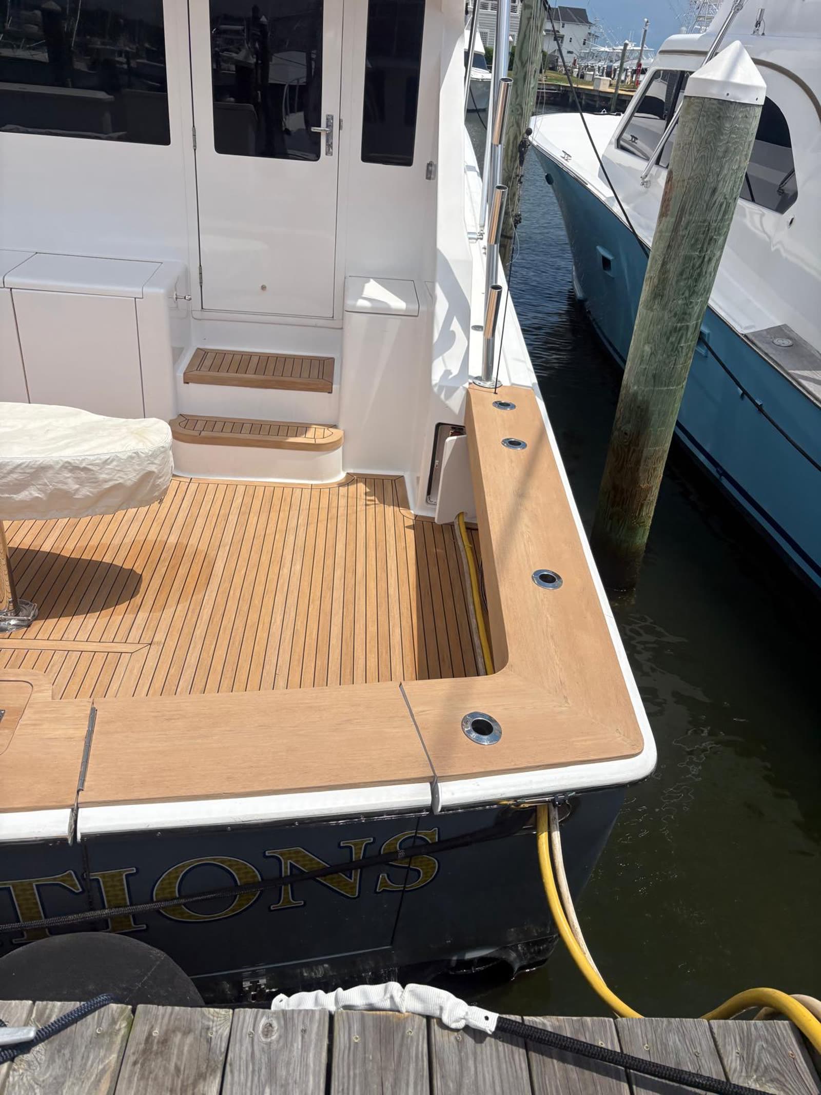 Synthetic teak gunwale cap running aft with flush stainless rod holders over dark water