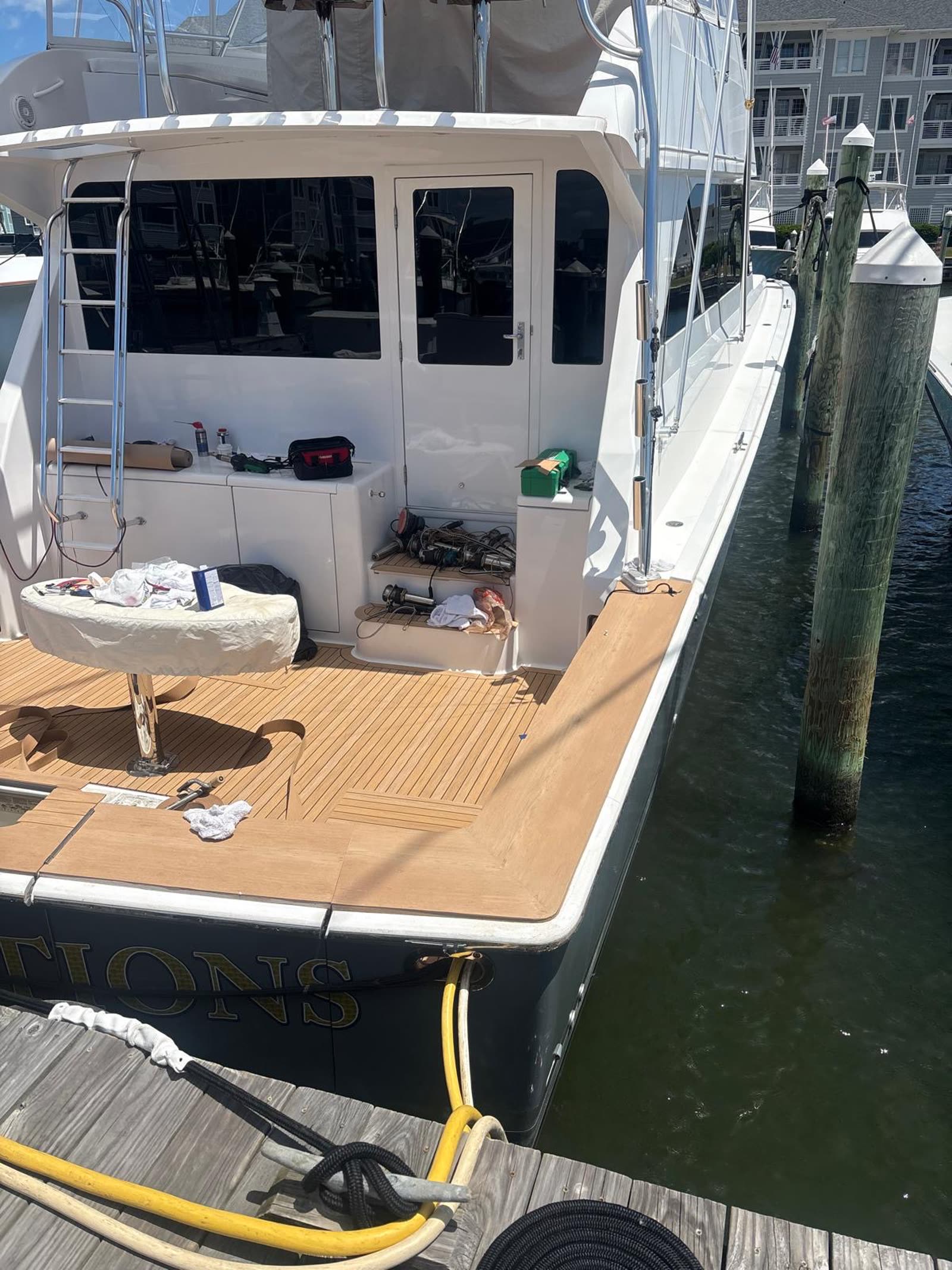 Sportfish alongside the dock mid-installation with new synthetic teak laid and tools still aboard
