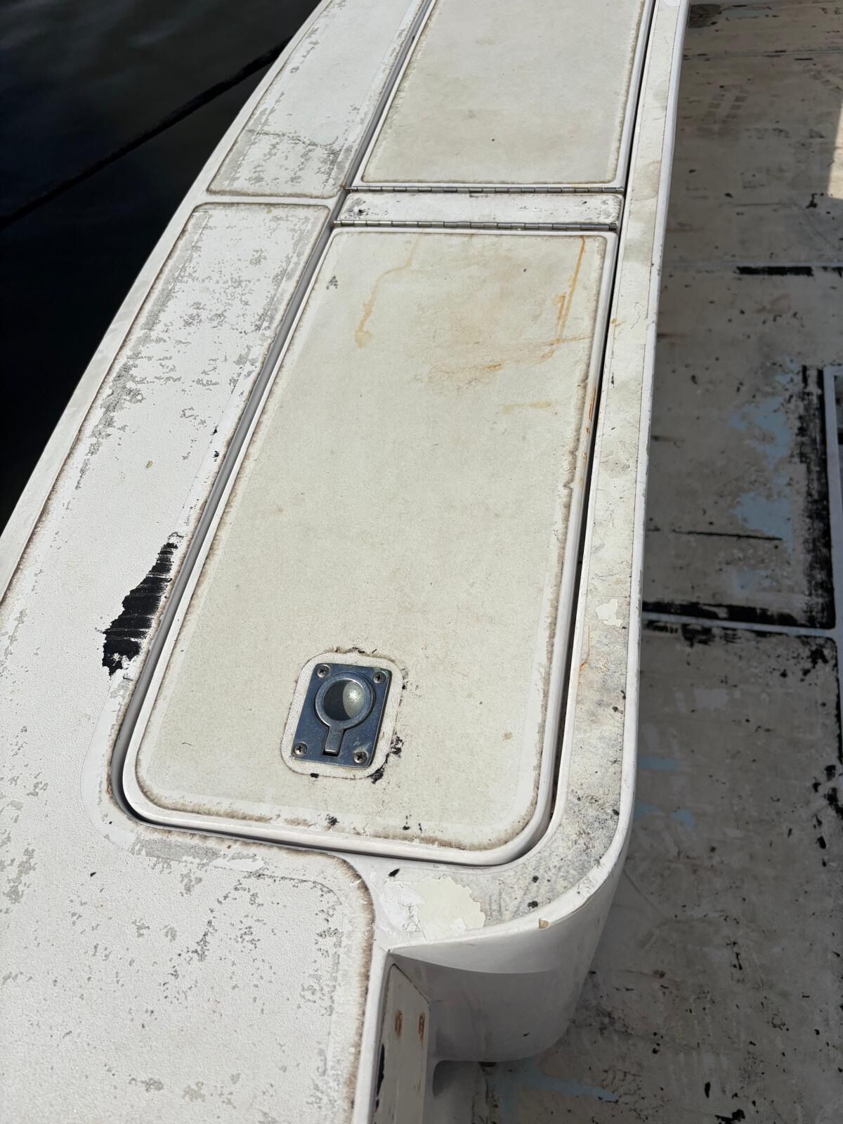 Weathered white gunwale locker lids with chalked gelcoat and adhesive residue before new synthetic teak is fitted