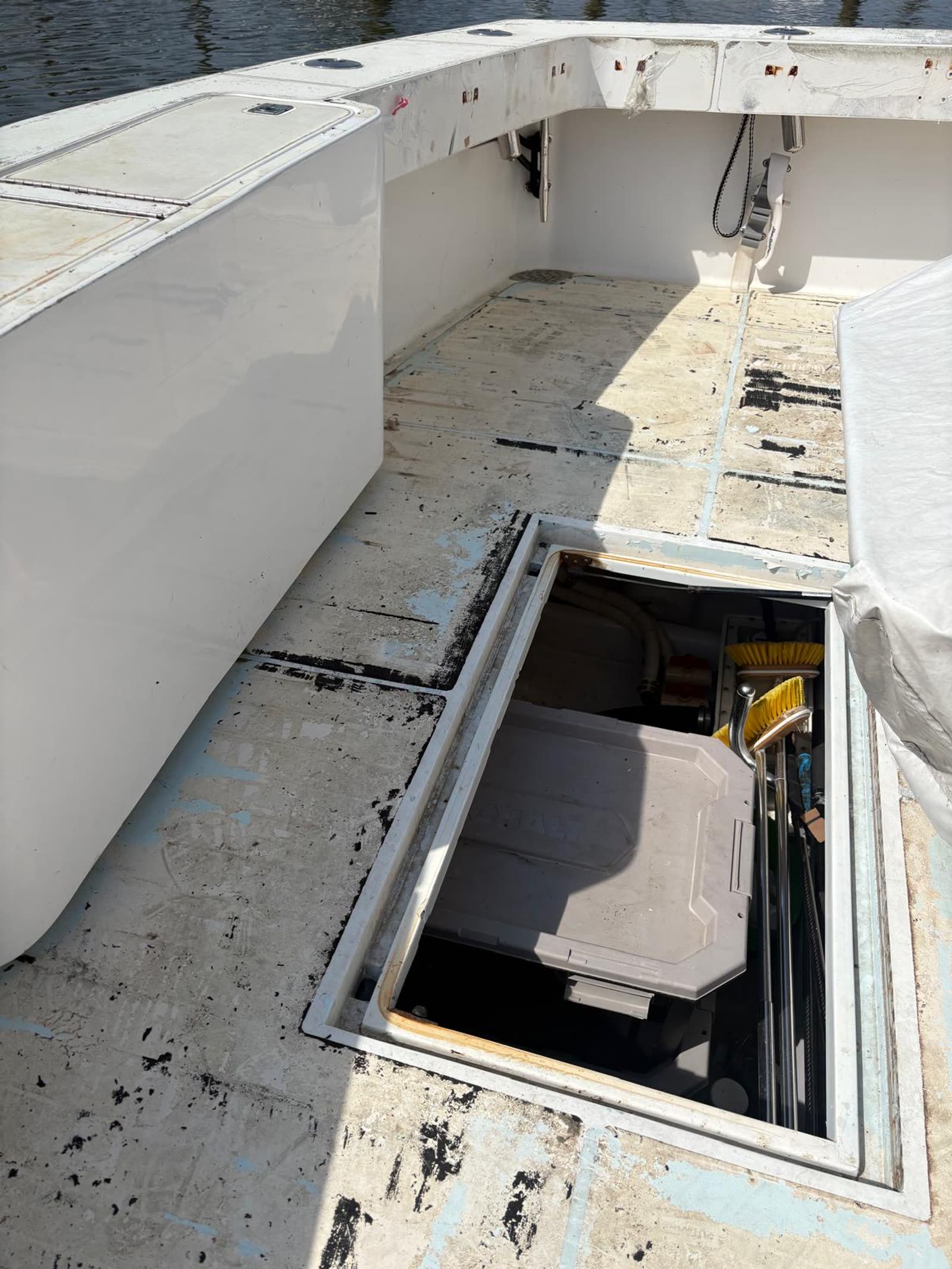 Sportfish cockpit stripped to bare fibreglass with black adhesive ridges and a deck locker hatch standing open