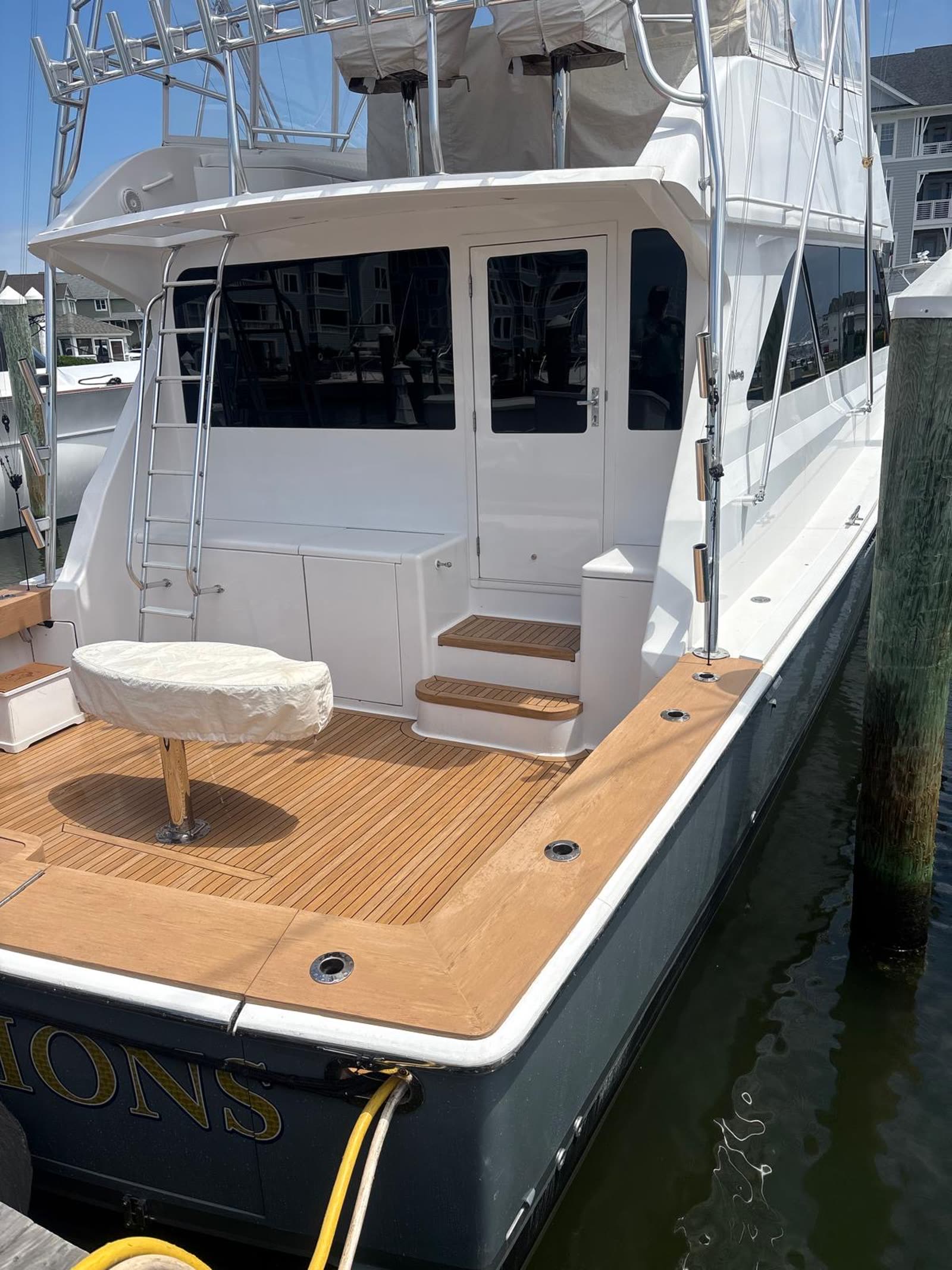 Dark-hulled sportfish alongside showing the finished synthetic teak cockpit, gunwale caps and boarding steps