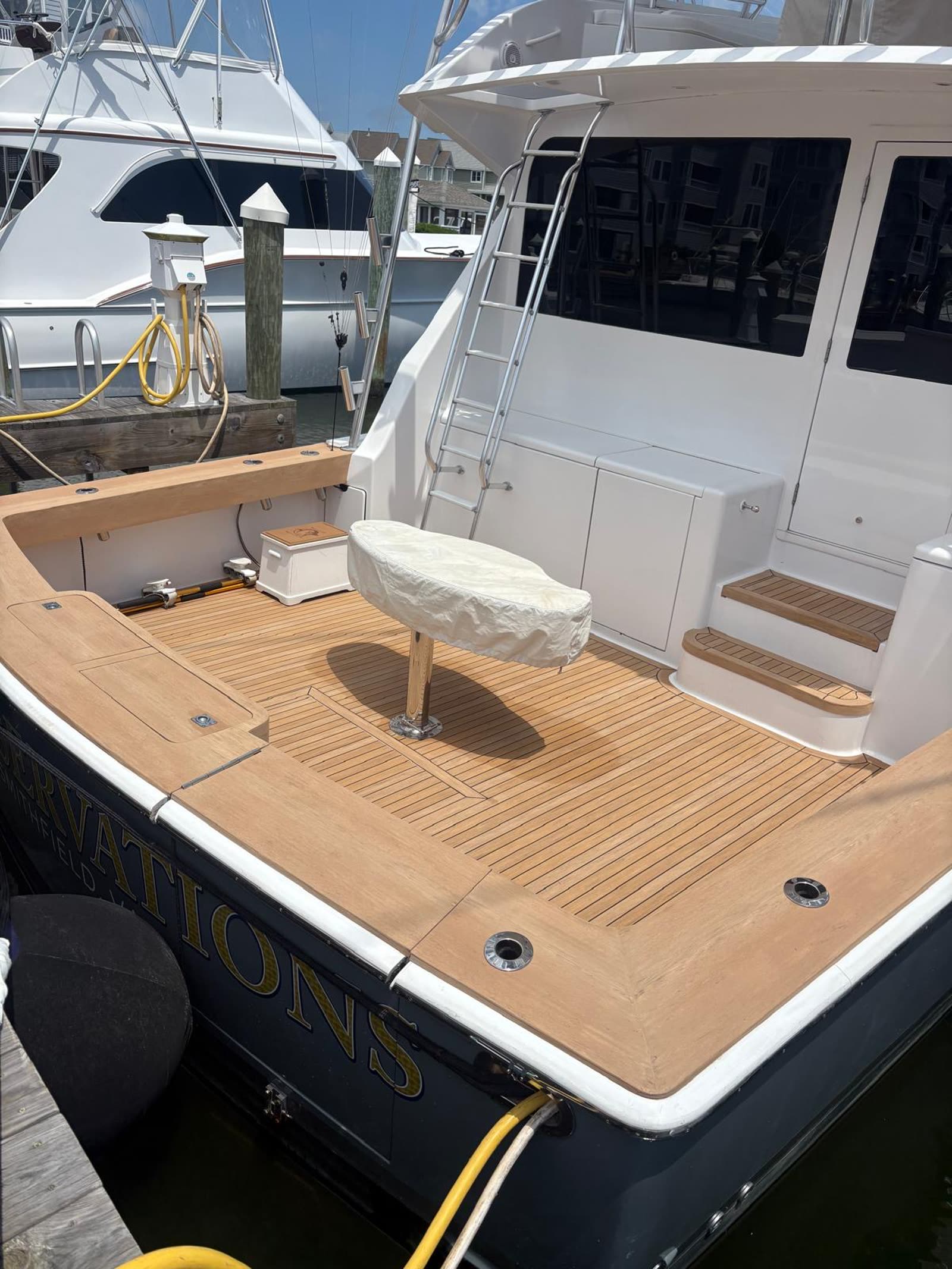 Wide view of a finished sportfish aft cockpit with synthetic teak deck, transom cap and boarding steps